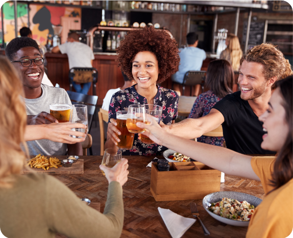 Group Of Young Friends Meeting For Drinks And Food Making A Toast In Restaurant