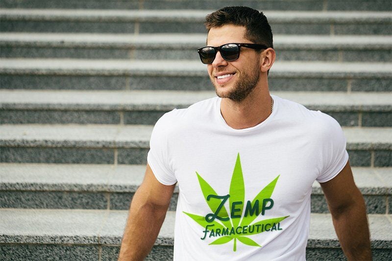 A happy young man wearing a Zemp Hemp t-shirt while leaning on a handrail in front of some stairs.